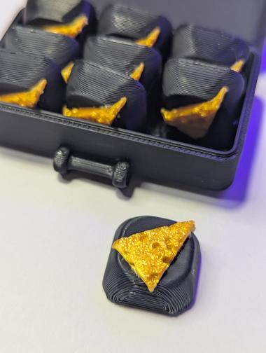 full box of cheese caps A full box of 9 keycaps sit behind a cap placed in front, they are custom wedge of cheese caps.