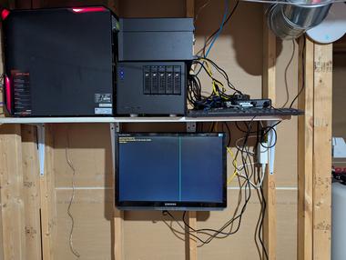 Homelab update Jul 2025 Basement shelf with 3 computers, a network switch, an uninterubptable power supply, one monitor underneath, and a wifi access point to…