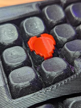 heart of a macropad A pixel heart kecap in the center of a macropad, the macropad is admittedly dirty, filled with small bits of fuzz.