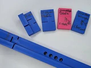 PXL_20251013_011946949.webp Experimental slices of 3d printed dovetails laid out in a fan.  Each have sharpie notes written on them.