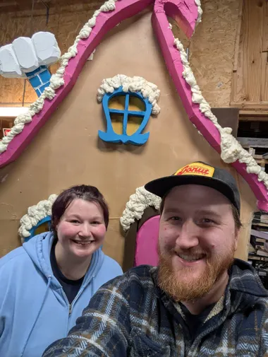 Finished Elf House Waylon and Rhiannon standing in front of a mostly finished elf house built for the Jolly Holiday Performance at the local theater.
